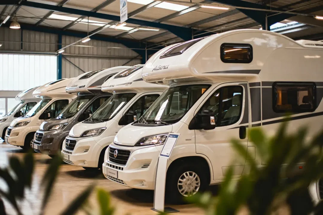 Rangée de camping-cars blancs alignés dans un showroom bien éclairé, vue intérieure industrielle.