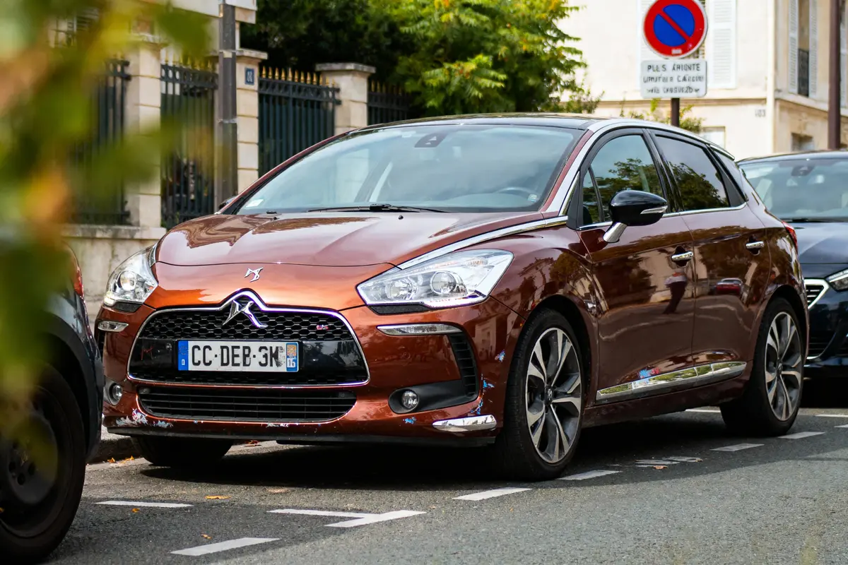 Voiture marron Citroën DS5 garée sur la route avec panneau de stationnement interdit en arrière-plan.