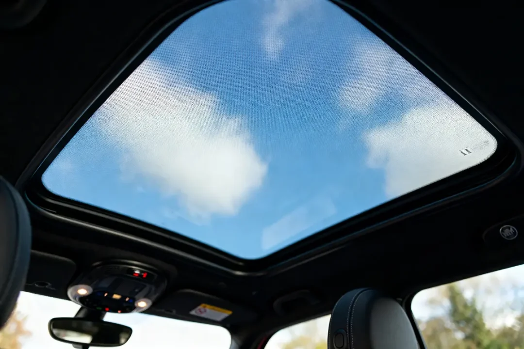 Vue à travers un toit panoramique de voiture, ciel bleu avec nuages.