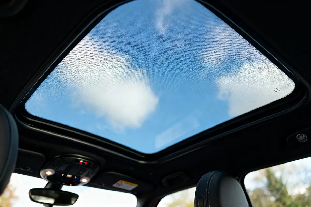 Vue à travers un toit panoramique de voiture, ciel bleu avec nuages.