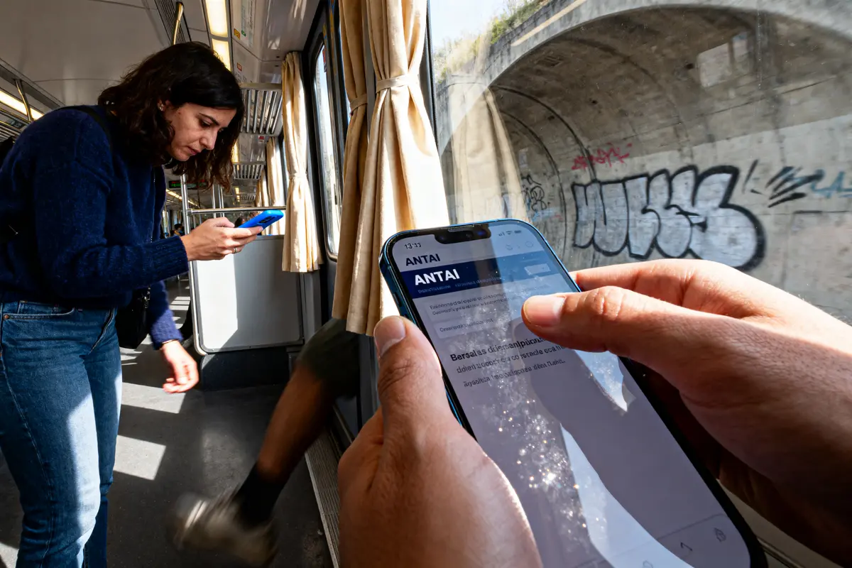 Personnes utilisant smartphones dans un train, tunnel avec graffitis visible à travers la fenêtre.
