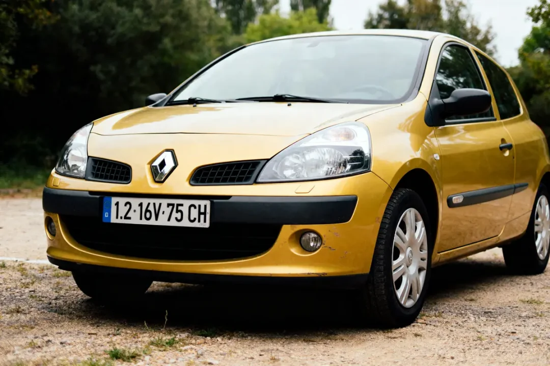 Voiture Renault Clio jaune garée à l'extérieur, immatriculation visible, arbres en arrière-plan.
