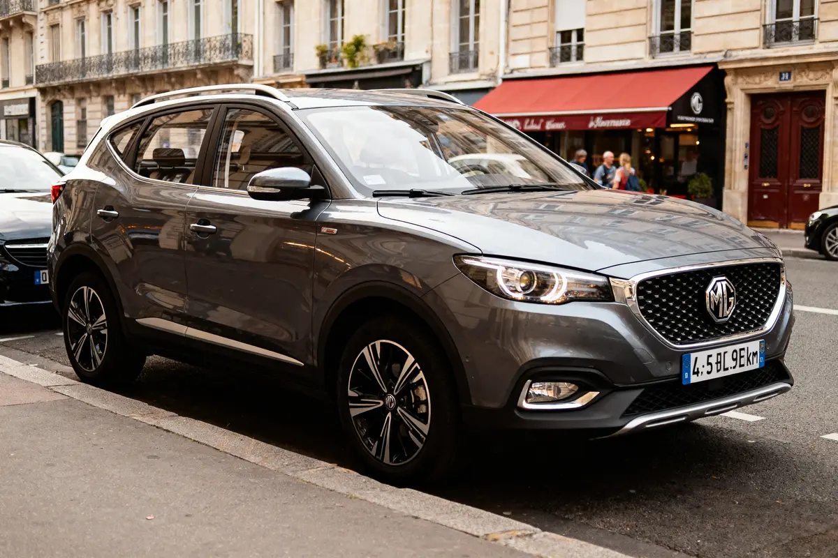 SUV gris MG garé à côté d'un café parisien avec store rouge.