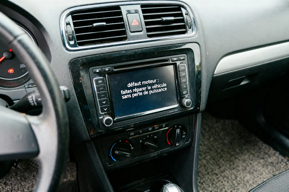 Écran de voiture affichant message de défaut moteur, recommandant réparation pour éviter perte de puissance.