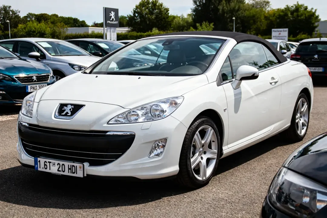 Voiture cabriolet blanche Peugeot 308 CC exposée sur un parking en extérieur