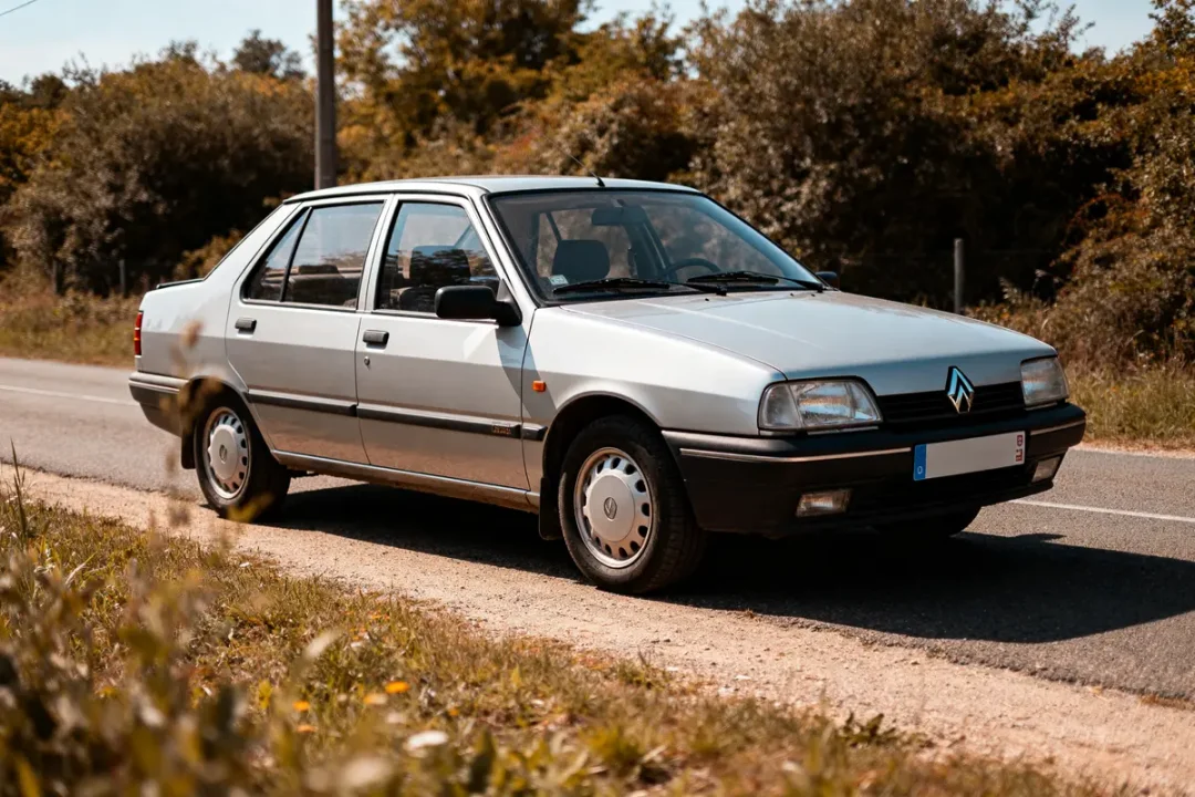 Renault 21 Sedan argentée garée sur une route de campagne en été