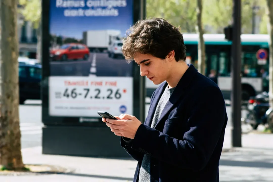 Jeune homme vérifiant sur son téléphone comment savoir si on a une amende.