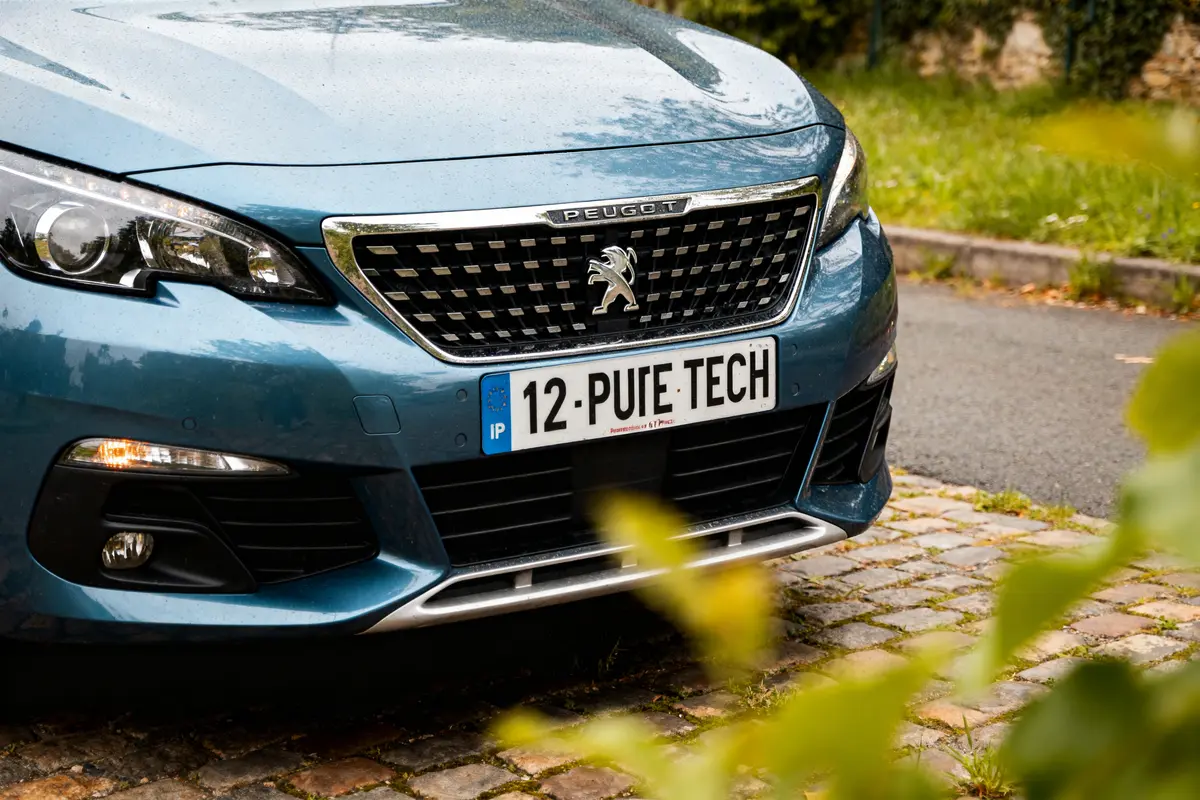 Avant de voiture Peugeot bleu sur briques avec moteur de Peugeot à éviter visible