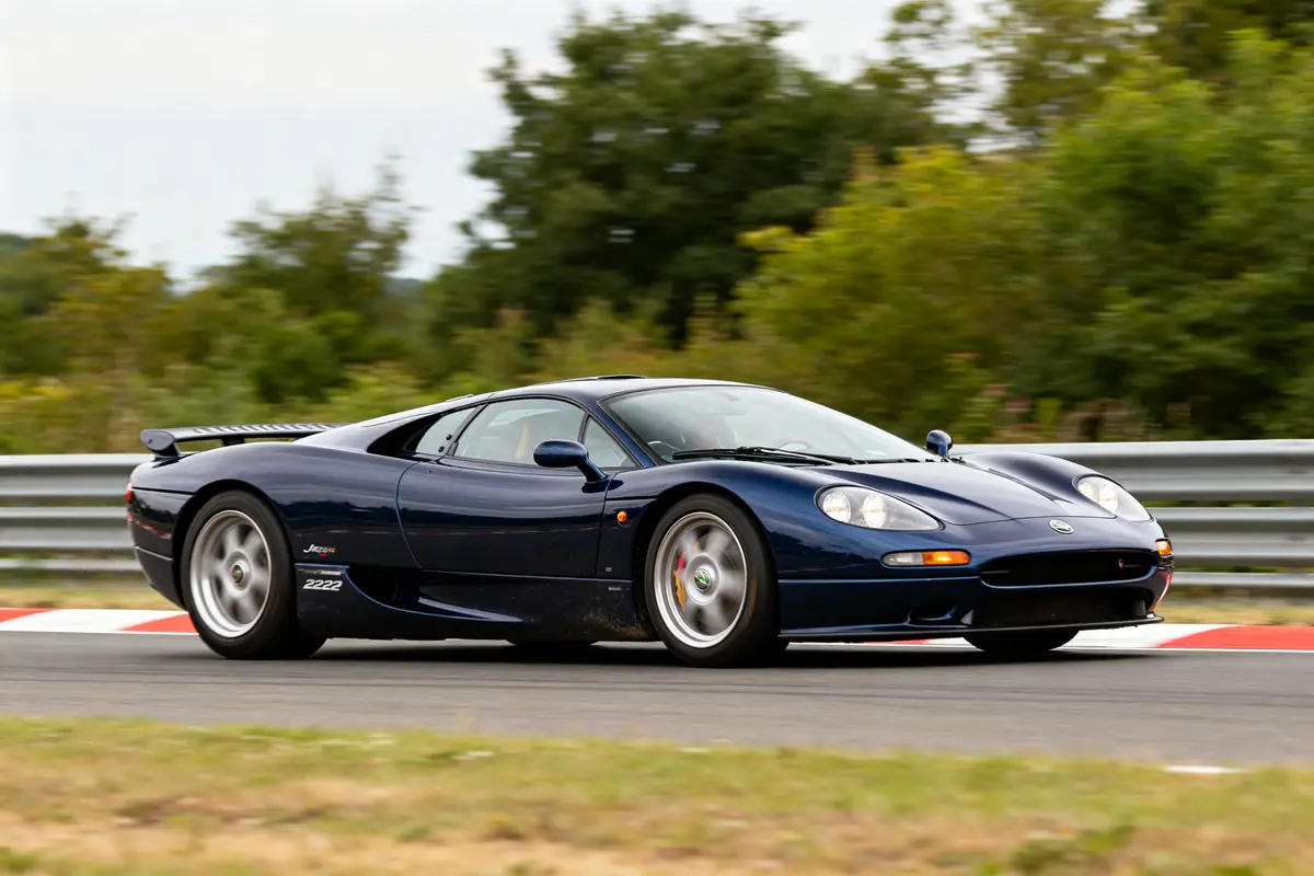 Supercar Jaguar XJ220 bleue sur circuit avec arbres en arrière-plan et garde-corps métallique