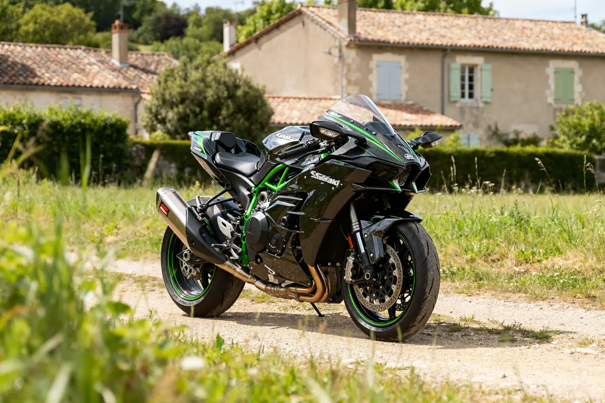 Kawasaki Ninja H2R garée sur chemin devant maisons en campagne verdoyante