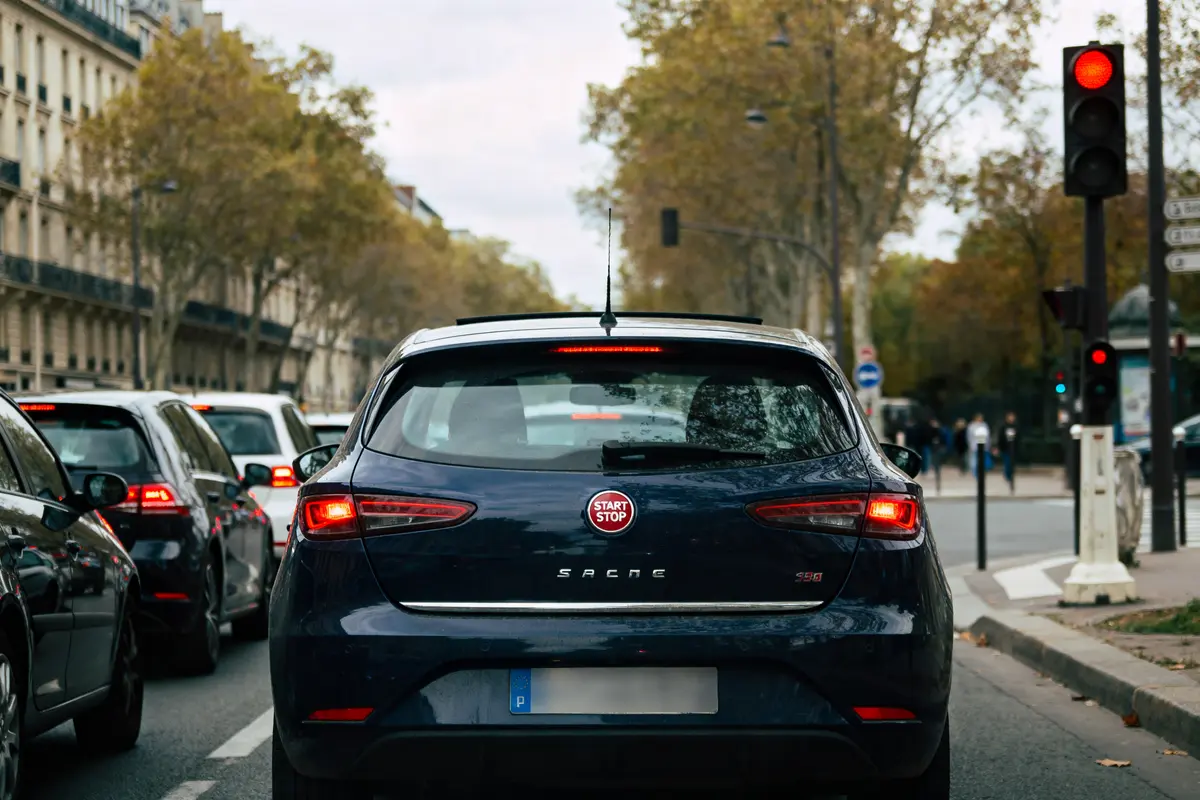 Véhicule en ville avec feu rouge et système Start and Stop activé à l'arrière.
