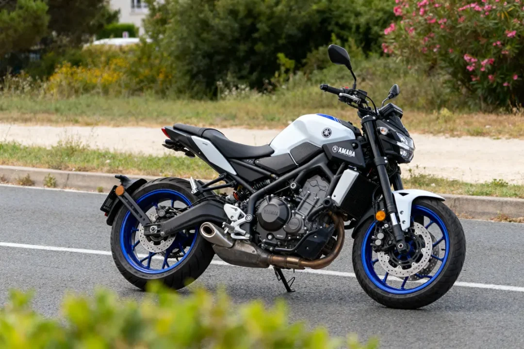Moto Yamaha MT-125 blanche et bleue stationnée sur route, vue latérale gauche