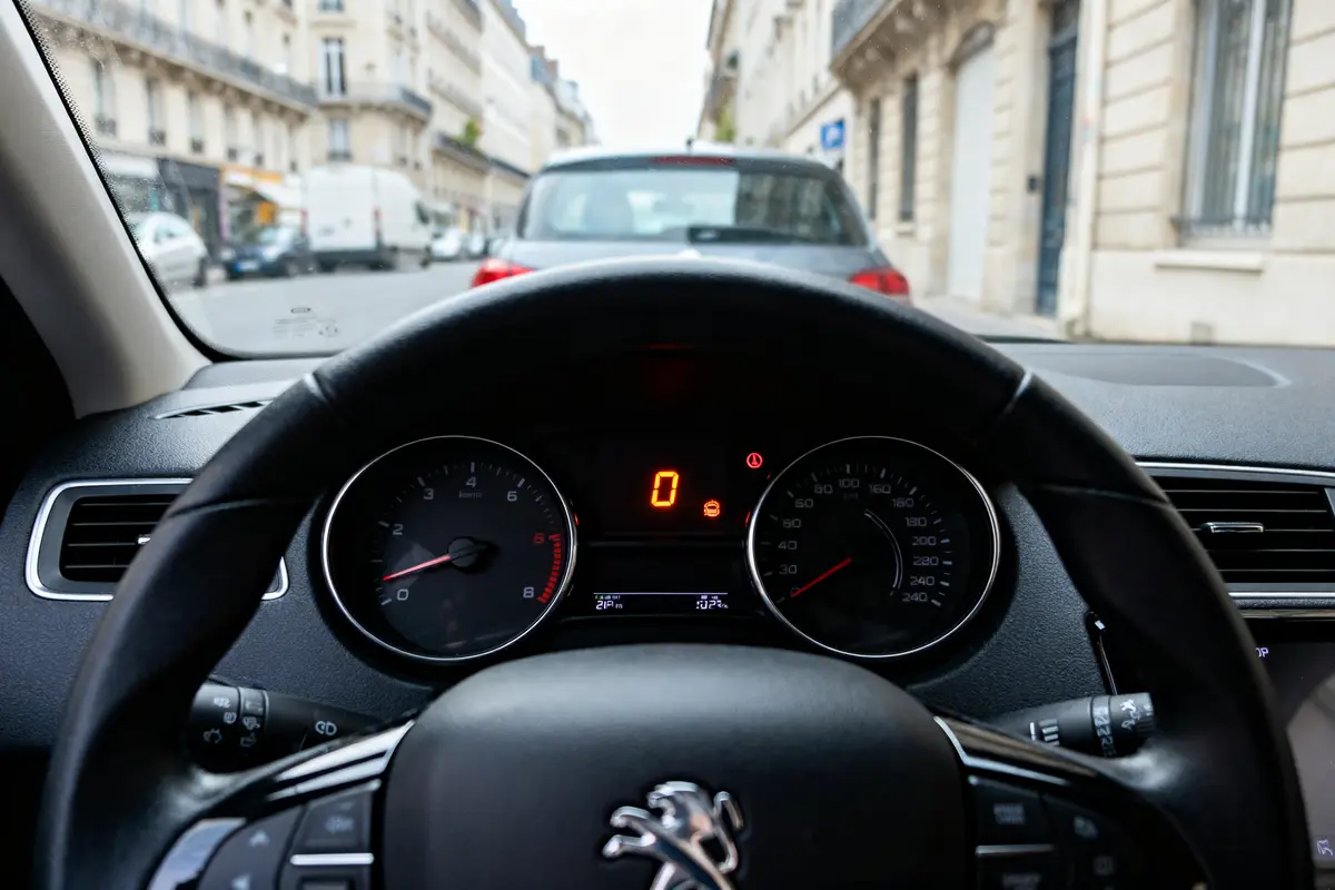 Tableau de bord d'une Peugeot 208 indiquant un défaut moteur sur un affichage urbain.