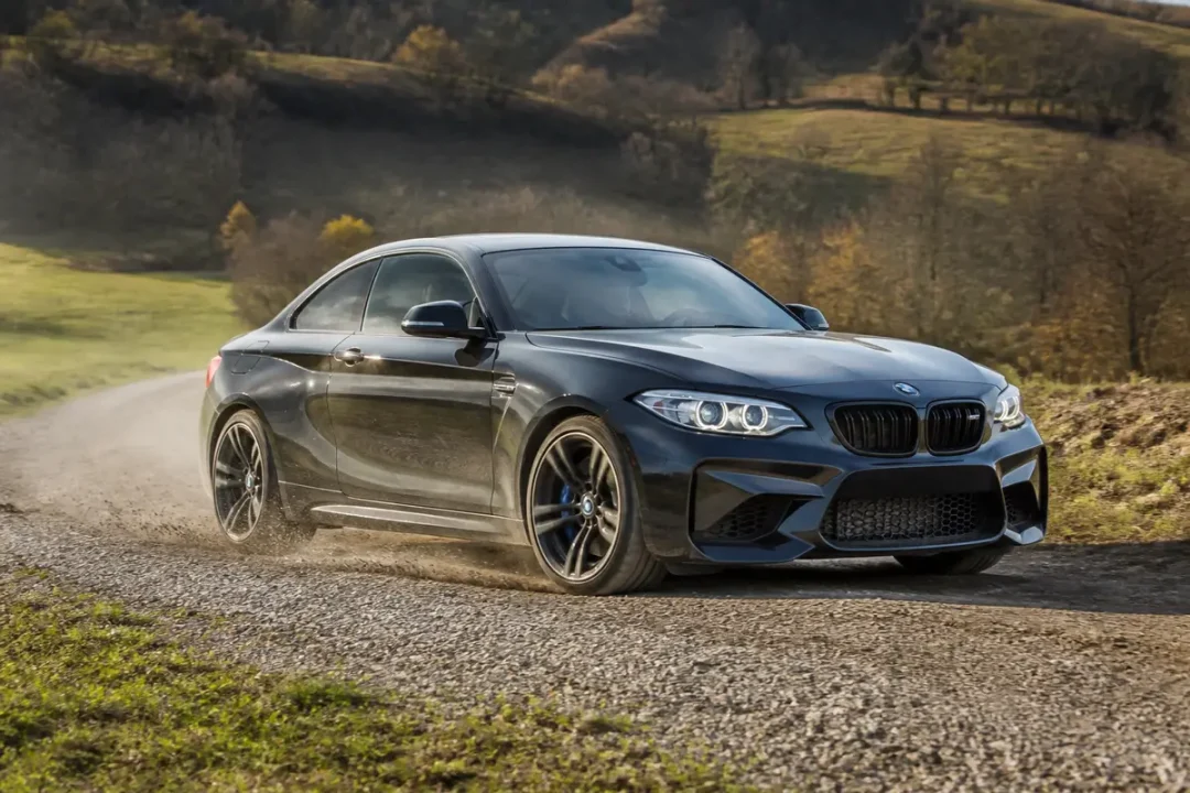 Voiture BMW noire roulant sur chemin de terre dans un paysage rural DTC BMW