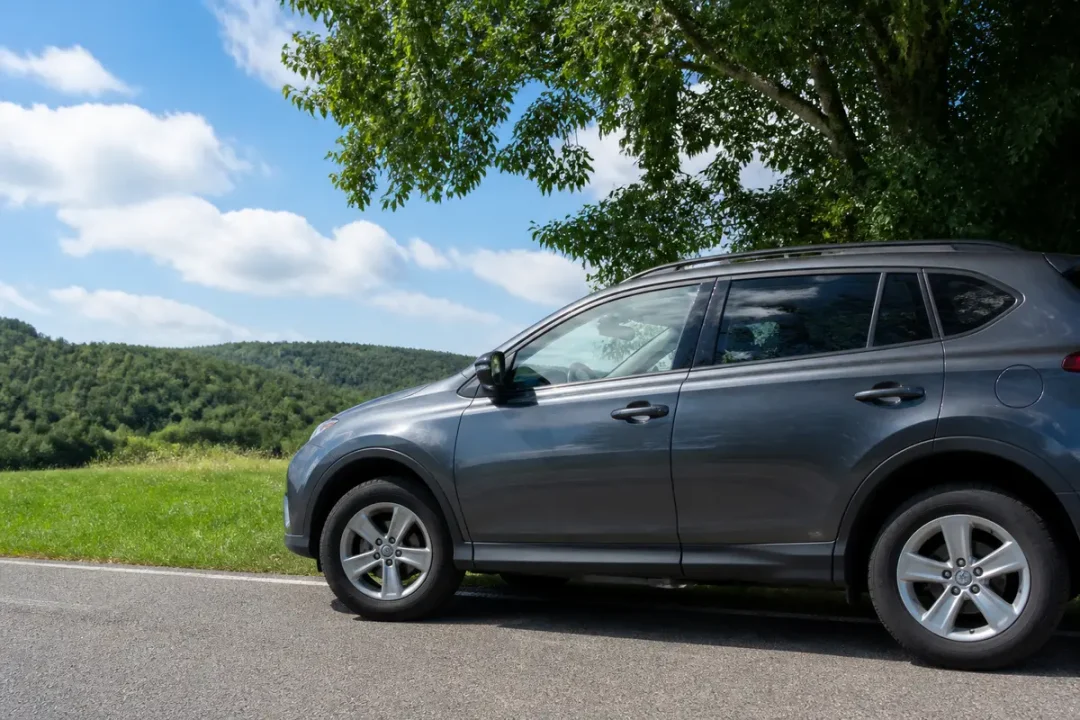 SUV d'occasion gris stationné au bord d'une route en campagne sous ciel bleu