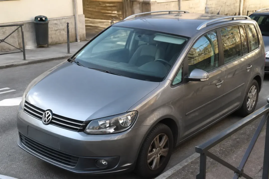Voiture grise garée, modèle Volkswagen Touran d'occasion en ville, vue de côté.