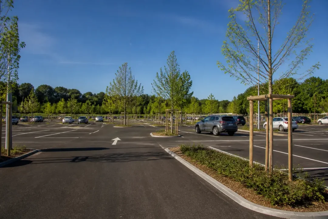 Parking vide avec voitures à l'aire de covoiturage de Parc Poullic arborée et ensoleillée
